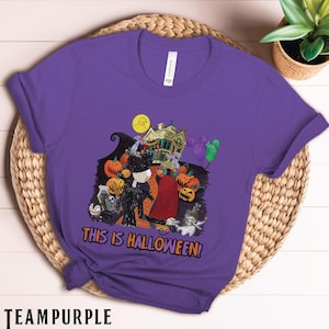 Puede incluir: Una camiseta morada con un dise&ntilde;o de Halloween. El dise&ntilde;o incluye a Jack Skellington, Sally, calabazas, una casa embrujada y el texto "THIS IS HALLOWEEN!". La camiseta est&aacute; hecha de un material suave.