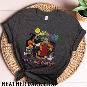 Puede incluir: Camiseta gris oscuro con un dise&ntilde;o de Halloween. El dise&ntilde;o incluye a Jack Skellington y Sally, calabazas, una casa embrujada y el texto "THIS IS HALLOWEEN!". Una camiseta divertida para Halloween. Hecha de material gris oscuro.