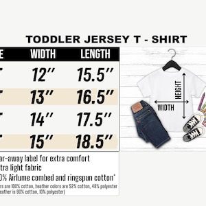 Op de afbeelding: Een wit peuter jersey t-shirt met maat- en meetgegevens. Het shirt wordt gepresenteerd met een blauwe spijkerbroek, zwarte sneakers en kleurpotloden. De afmetingen zijn in cm: breedte van 30,48 cm tot 38,1 cm, lengte van 39,37 cm tot 46,99 cm.