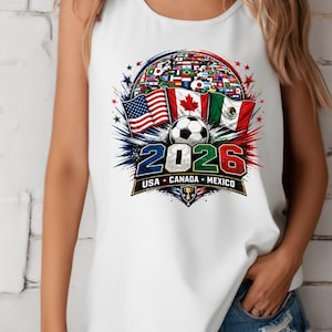 May include: A white sleeveless tank top featuring a graphic print of a soccer ball, the flags of the USA, Canada, and Mexico, and a globe filled with international flags. The text 2026 and USA CANADA MEXICO are printed below the soccer ball graphic.