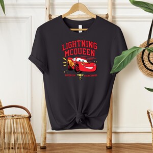 May include: Black t-shirt with a red cartoon race car, the text "Lightning McQueen", and the words "Piston Cup Racing Series".