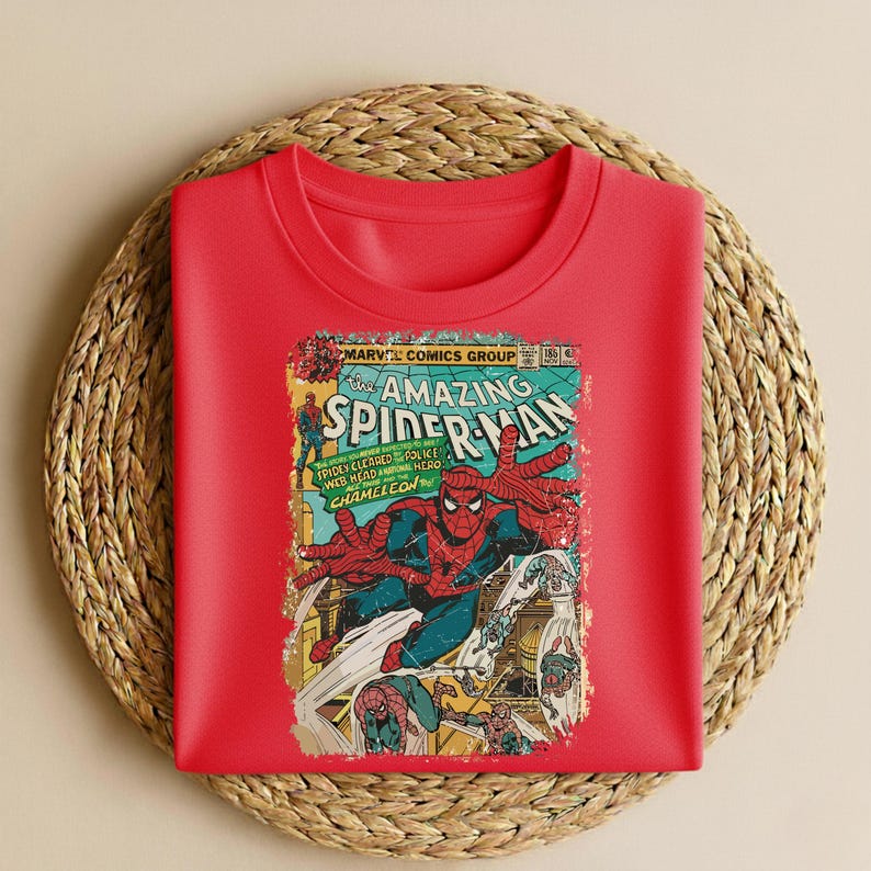 May include: A red crew neck sweatshirt featuring a vintage comic book cover of The Amazing Spider-Man. The comic book cover has a distressed look with Spider-Man in action, with text that reads "Marvel Comics Group".