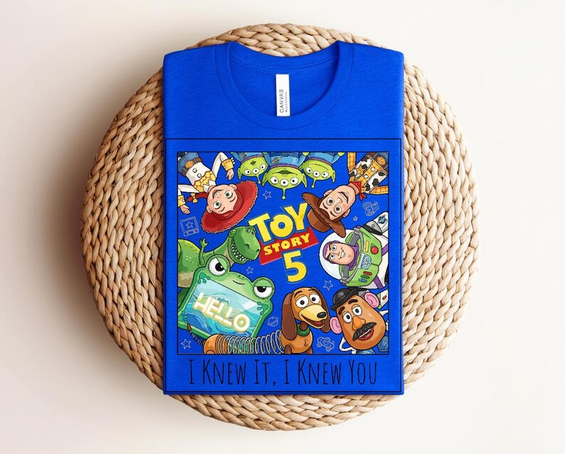 K&ouml;nnte beinhalten: Ein k&ouml;nigsblaues T-Shirt mit einem Toy Story 5-Grafikdruck, der Charaktere wie Woody, Buzz Lightyear, Jessie, Rex, Slinky Dog, Mr. Potato Head und Aliens zeigt. Das Design enth&auml;lt den Text Toy Story 5 und I Knew It, I Knew You.