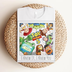 K&ouml;nnte beinhalten: Ein wei&szlig;es T-Shirt mit einem farbenfrohen Grafikdruck der Toy Story-Figuren, darunter Woody, Buzz Lightyear, Jessie, Rex, Slinky Dog, Mr. Potato Head und die Aliens. Der Text lautet TOY STORY 5 und I KNEW IT, I KNEW YOU.