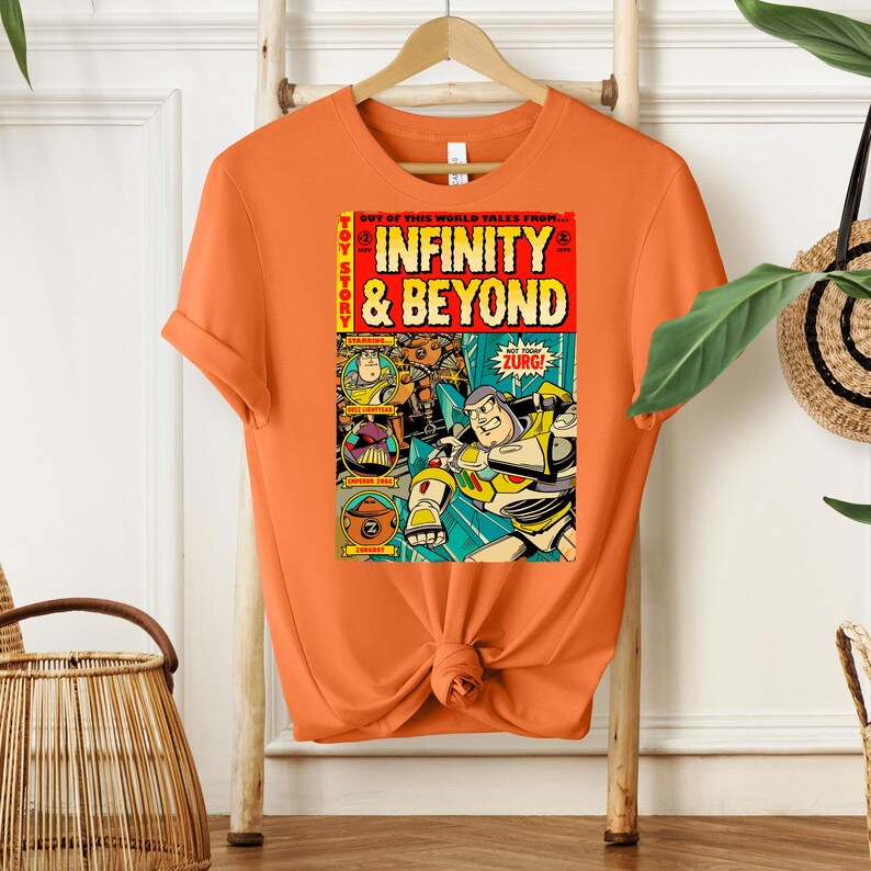 Puede incluir: Camiseta naranja con un dise&ntilde;o de c&oacute;mic vintage con personajes de la franquicia de pel&iacute;culas Toy Story. La portada del c&oacute;mic dice "Toy Story Infinity & Beyond" con una imagen de Buzz Lightyear y otros personajes.