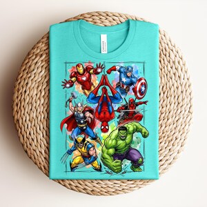 May include: A turquoise t-shirt with a vibrant graphic of superheroes such as Iron Man, Captain America, Spider-Man, Thor, Wolverine, Hulk, and Deadpool. The design is framed with a watercolour-style border.