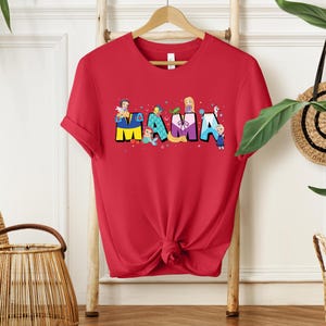 K&ouml;nnte beinhalten: Rotes T-Shirt mit einem Aufdruck des Wortes "MAMA", das mit Disney-Prinzessinnen ausgeschrieben ist. Jeder Buchstabe ist eine andere Prinzessin, und jede Prinzessin tr&auml;gt ihr charakteristisches Outfit.