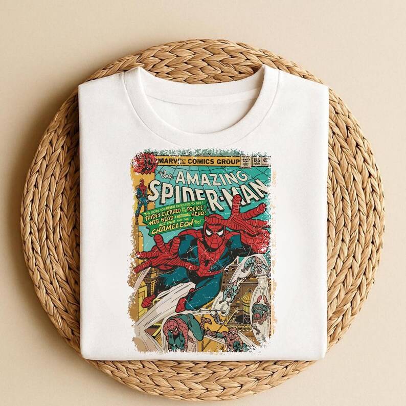 May include: White t-shirt featuring a vintage comic book cover design. The graphic showcases Spider-Man in action, with the title "The Amazing Spider-Man" prominently displayed. The design includes text that reads "Marvel Comics Group".