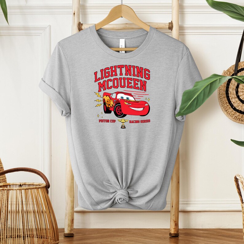 May include: Gray t-shirt with a red cartoon race car and the text "Lightning McQueen Piston Cup Racing Series".