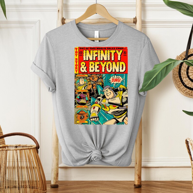 Puede incluir: Una camiseta gris con un dise&ntilde;o de portada de c&oacute;mic vintage con personajes de la franquicia Toy Story. La portada del c&oacute;mic se titula "Infinity & Beyond" y presenta a Buzz Lightyear y otros personajes de la pel&iacute;cula.