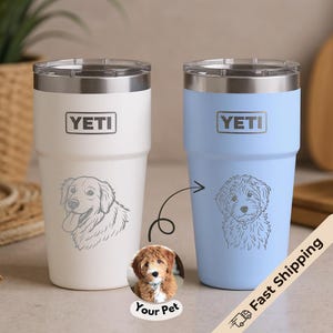 May include: Two Yeti tumblers, one white and one light blue, each with a pet portrait. The white tumbler features a golden retriever, and the blue one has a doodle. Both have the Yeti logo.