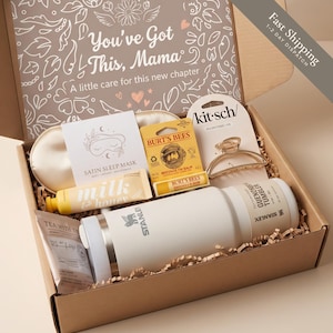 May include: A gift box containing a white Stanley tumbler, a Burt's Bees lip balm, a Kitsch hair clip, a satin sleep mask, a tube of milk and honey lotion, and a tea bag. The box lid features the text You've Got This, Mama and A little care for this new chapter.