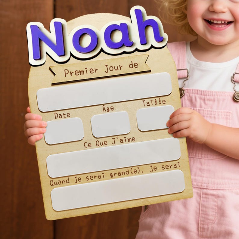 May include: Wooden sign with the name "Noah" in blue letters. The sign has spaces to record information about a child's first day, including date, age, and height. The text "Premier Jour de" is also visible.