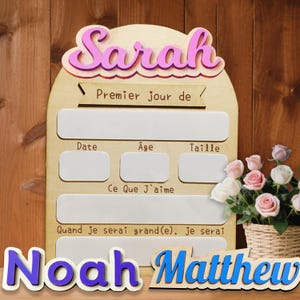 May include: A wooden milestone board with the name "Sarah" in pink and a space for "Premier jour de". Includes sections for date, age, and size, with the text "Ce Que J'aime" and "Quand je serai grand(e), je serai". The name "Noah Matthew" is at the bottom.