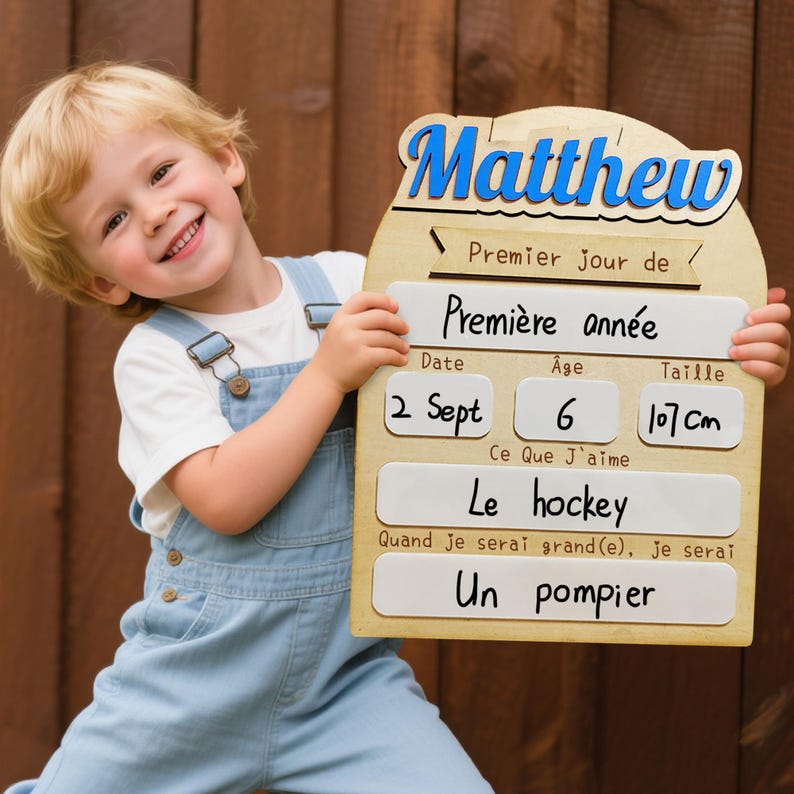 May include: A wooden sign with the name "Matthew" in blue script. The sign includes information about the child's first day of school, age 6, height 107 cm, and favorite hobby, hockey. The sign also states the child wants to be a firefighter.