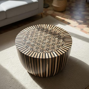 Puede incluir: Una mesa de centro redonda con un diseño geométrico. La superficie presenta un patrón de estrella, mientras que los lados tienen rayas verticales. La mesa está hecha de madera y tiene un acabado natural, agregando un toque de elegancia.