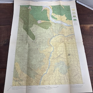 May include: A vintage topographic map with a detailed depiction of a geographical area. The map features a color palette of greens, browns, and blues, with grid lines and text labels. The map is folded and appears to be aged.