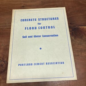 May include: A rectangular booklet with a cream-colored cover and blue text that reads: CONCRETE STRUCTURES for FLOOD CONTROL, Soil and Water Conservation, and PORTLAND CEMENT ASSOCIATION. The cover features a thin blue border and a small blue dot.