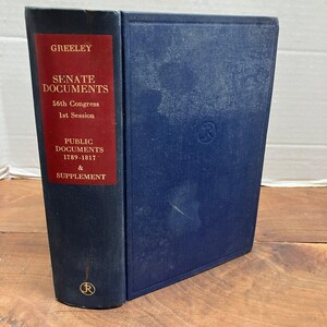 May include: A hardbound book with a dark blue cover and a red spine label. The text on the spine reads: GREELEY, SENATE DOCUMENTS, 56th Congress, 1st Session, PUBLIC DOCUMENTS, 1789-1817 & SUPPLEMENT. A circular logo is embossed on the front cover and spine.