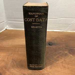 May include: A vintage hardcover book titled Handbook of Cost Data by Gillette, published by McGraw-Hill Book Company. The book features a dark, textured black cover with gold embossed lettering on the spine, showing signs of age and wear.