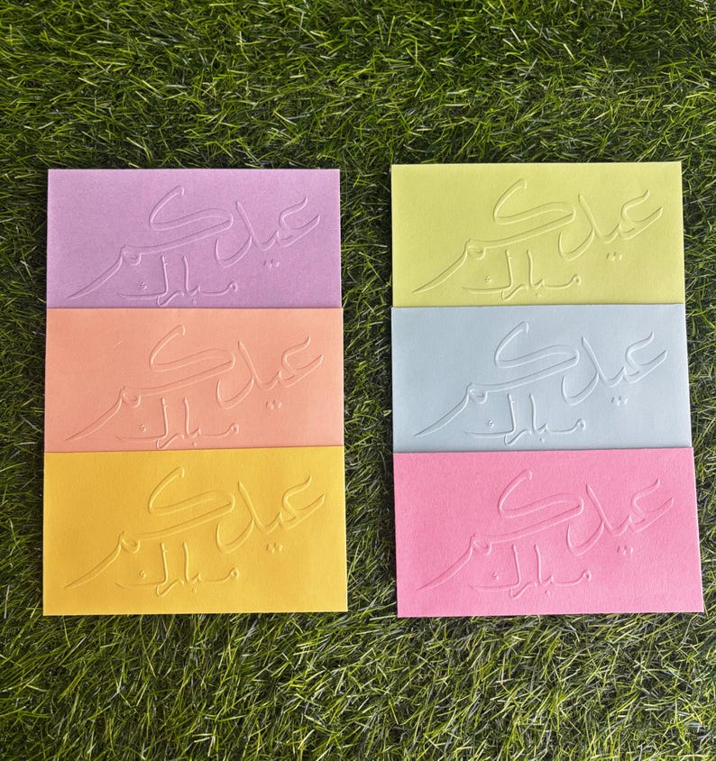 Puede incluir: Seis tarjetas de felicitaci&oacute;n con caligraf&iacute;a &aacute;rabe en relieve en varios colores, incluyendo rosa, naranja, amarillo y azul. Las tarjetas presentan la frase "Eid Mubarak" en &aacute;rabe.