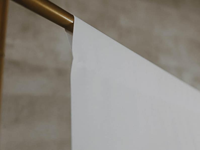 Puede incluir: Un tel&oacute;n de fondo blanco colgado de una varilla de metal dorado. El tel&oacute;n de fondo es liso y sin arrugas.