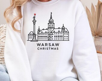 Może przedstawiać: Biała bluza z czarnym rysunkiem linii budynku i napisem "WARSAW CHRISTMAS". Czerwona gwiazda znajduje się na szczycie budynku. Słowo "WHITE" znajduje się na dole bluzy.