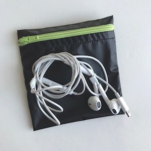 May include: A black zippered pouch with a lime green zipper. White earbuds are inside the pouch.
