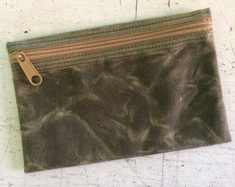 May include: A green canvas zippered pouch with a brown zipper.