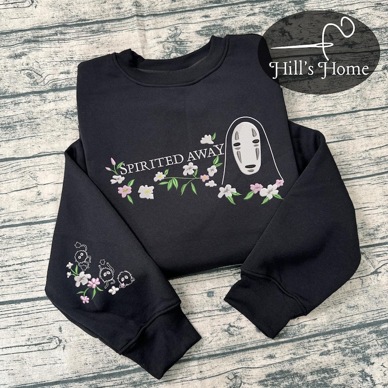 Puede incluir: Sudadera negra con detalles florales bordados y el texto "Spirited Away". El dise&ntilde;o incluye un personaje de la pel&iacute;cula de animaci&oacute;n. La manga tiene personajes y flores bordadas adicionales.