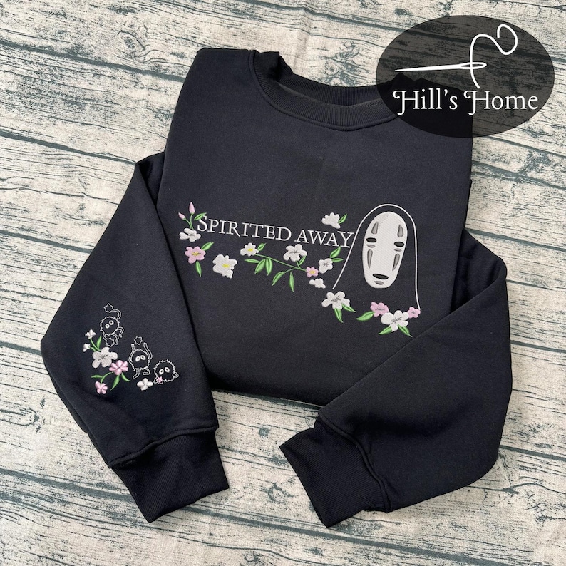 Puede incluir: Sudadera negra de cuello redondo con dise&ntilde;o bordado. Presenta el texto "Spirited Away" con una rama floral y un personaje de la pel&iacute;cula. La manga izquierda tiene un dise&ntilde;o bordado de tres peque&ntilde;os personajes y flores.