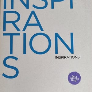 May include: A white magazine cover with the word "INSPIRATIONS" in large, blue, sans-serif font. Below, smaller text reads "INSPIRATIONS". A purple circle indicates "FALL WINTER 12-13". The bottom of the cover displays "Peclers Paris".