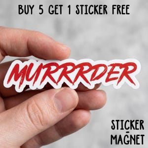 May include: A white sticker with the word "MURRRDER" in red, brush-style lettering. The sticker is held in a hand. Above the sticker, the text reads "BUY 5 GET 1 STICKER FREE". Below the sticker, the text reads "STICKER MAGNET".