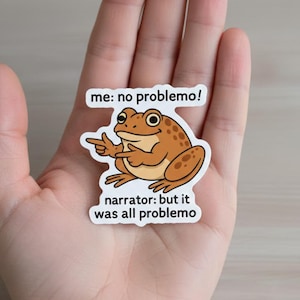 May include: A sticker featuring a cartoon frog with the text "me: no problemo!" above it and "narrator: but it was all problemo" below. The frog is brown with darker spots and is pointing with one hand.