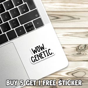 Op de afbeelding: Een witte sticker met de woorden "WOW. GENETIC." in een zwarte, vette letter. De sticker staat op een zilveren laptop, met een houten achtergrond. De tekst "BUY 5 GET 1 FREE STICKER" staat onderaan.
