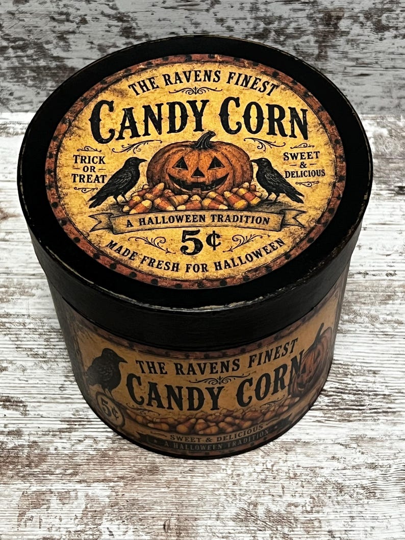 May include: A round black container with a vintage-style label featuring a jack-o'-lantern, two black ravens, and candy corn. The text reads: THE RAVENS FINEST CANDY CORN, TRICK OR TREAT, SWEET & DELICIOUS, A HALLOWEEN TRADITION, 5&cent;, MADE FRESH FOR HALLOWEEN.