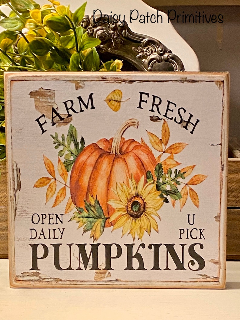 May include: A rustic wooden sign with a distressed white background features a watercolor illustration of a pumpkin and sunflower. The sign reads "Farm Fresh Pumpkins" with "Open Daily U Pick" text.