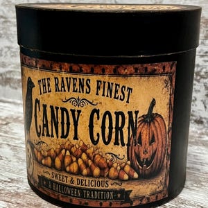 May include: A round black container with a vintage-style label featuring a black raven, a pile of candy corn, and a jack-o'-lantern. The text reads: The Ravens Finest Candy Corn, Sweet & Delicious, A Halloween Tradition.