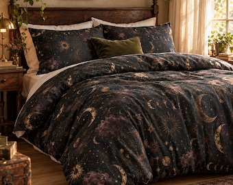 May include: A dark-colored duvet cover and matching pillowcases featuring a celestial print of golden suns, moons, and stars against a deep black background with purple nebula clouds. A solid olive green rectangular throw pillow sits in the center.