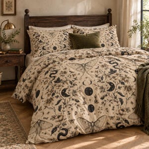 May include: A beige duvet cover and matching pillowcases featuring a black botanical print of moths, snakes, and moon phases. A solid olive green rectangular throw pillow rests on the bed, which is framed by a dark wooden headboard.