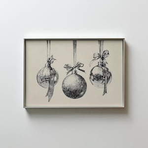 Puede incluir: Una impresión enmarcada que presenta tres adornos navideños en blanco y negro. Cada adorno está suspendido por una cinta y adornado con un lazo. La obra de arte tiene una estética vintage y esbozada, ideal para la decoración navideña.