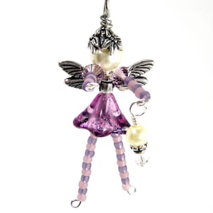 May include: A purple and silver beaded fairy charm with wings, a pearl, and a crystal pendant.