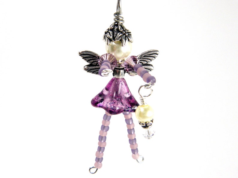 May include: A purple and silver beaded fairy charm with wings, a pearl, and a crystal pendant.