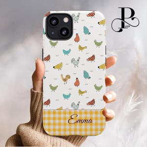 Peut inclure: Une coque de téléphone blanche avec un motif de poulets colorés et un fond à carreaux jaune et blanc. Le nom "Emma" est imprimé au bas de la coque.
