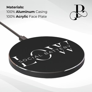 May include: A black wireless charging pad with a white logo that says "SOCIAL BATTERY" in a circular design. The charging pad is made of aluminum and acrylic.