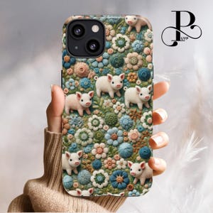 May include: A phone case with a floral pattern featuring small white pig figurines. The case has a green, blue, and pink floral design with a textured look.