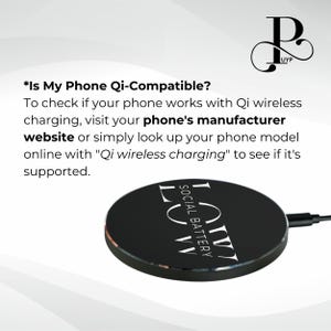 May include: A black wireless charging pad with the text "SOCIAL BATTERY" and "LVW" printed in white. The text "*Is My Phone Qi-Compatible?" is displayed above the charging pad. The text explains that to check if a phone is Qi-compatible, visit the phone's manufacturer website or search online for "Qi wireless charging".