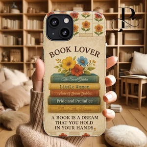 Op de afbeelding: Een telefoonhoesje met een vintage uitstraling met een stapel boeken met titels zoals "De geheime tuin", "Little Women" en "Anne of Green Gables". De hoes heeft ook een bloemenpatroon en de tekst "Book Lover" en "Een boek is een droom die je in je handen houdt."