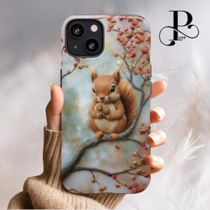 Op de afbeelding: Een telefoonhoesje met een schattig eekhoorn dat een noot vasthoudt, omringd door een bloemenontwerp met roze en rode bloemen op een blauwe en witte achtergrond.
