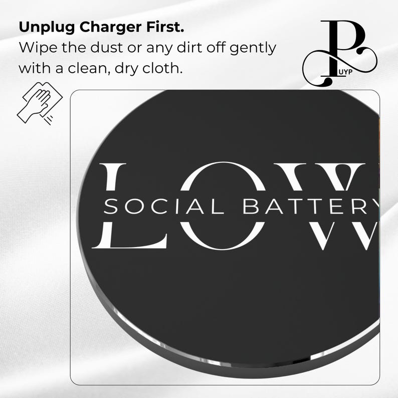 May include: A black round phone charger with the text "LOW SOCIAL BATTERY" in white lettering. The charger is on a white surface.